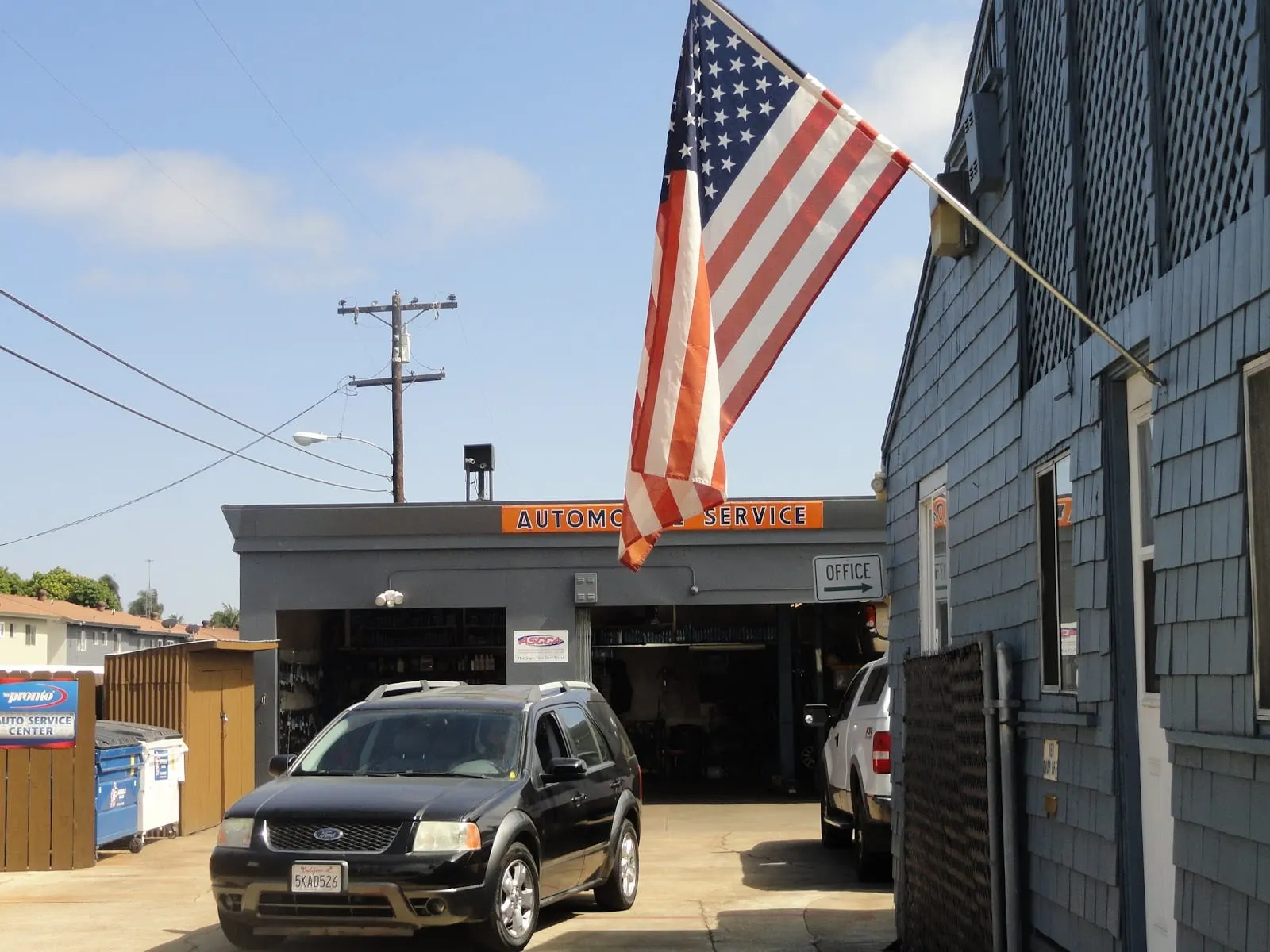 Becka Automotive shop front with flag and a black SUV